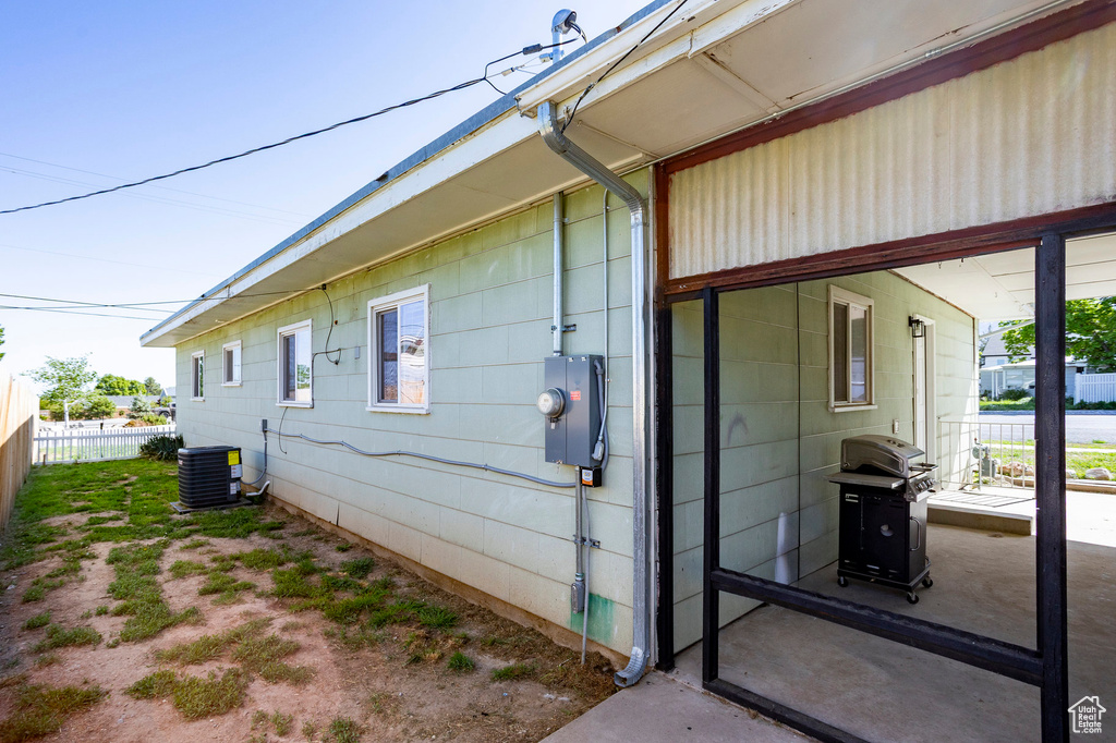 View of side of property with central air condition unit and fence