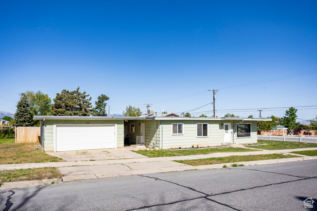 Ranch-style house featuring an attached garage, concrete driveway, and fence