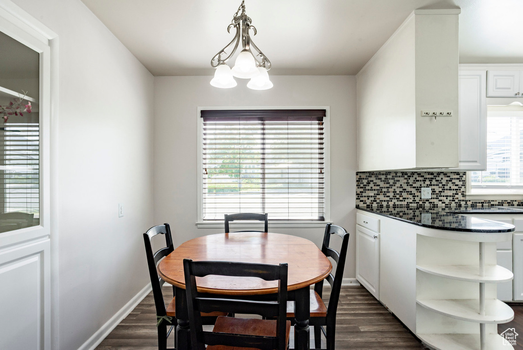 Dining area featuring dark wood finished floors, a chandelier, and baseboards