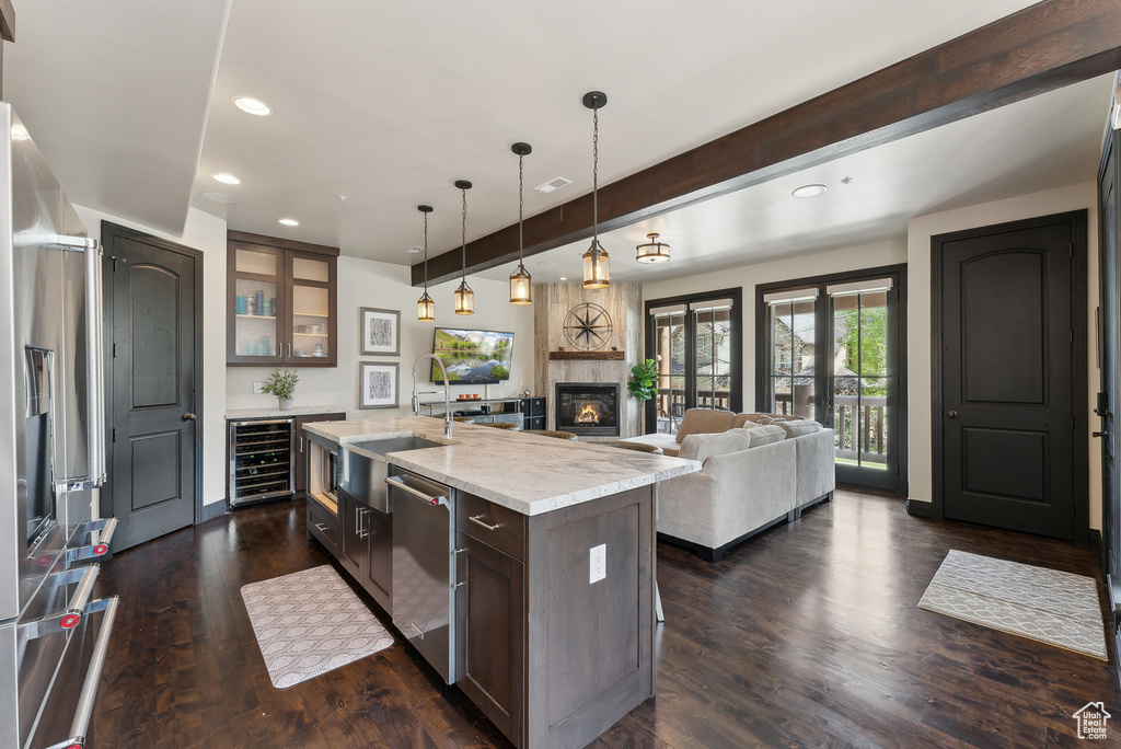 Kitchen featuring wine cooler, stainless steel appliances, beamed ceiling, a sink, and glass insert cabinets