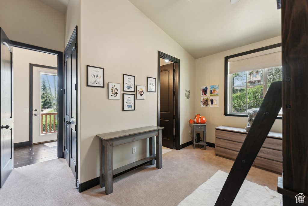 Hall featuring lofted ceiling, light colored carpet, and baseboards