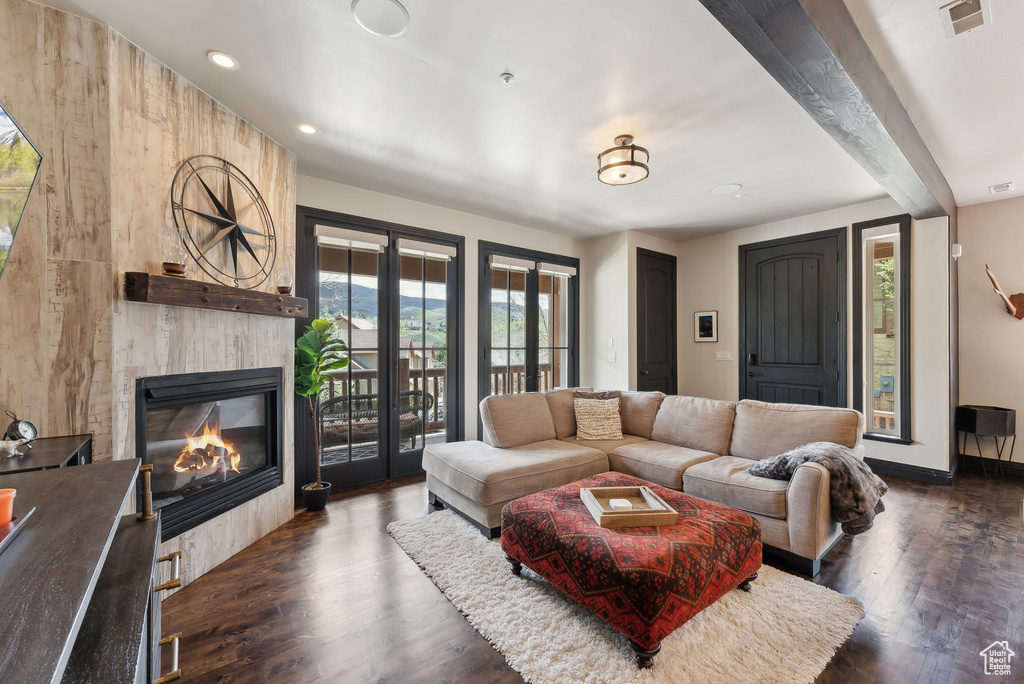 Living area featuring a large fireplace, dark wood-style floors, recessed lighting, beam ceiling, and baseboards