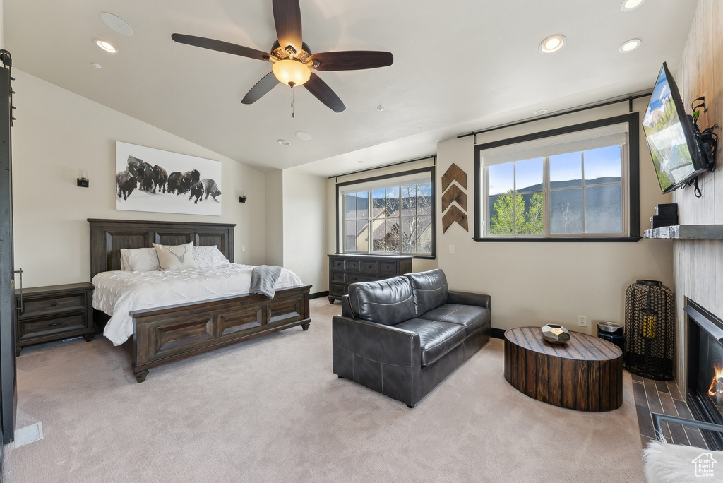 Bedroom with recessed lighting, light colored carpet, a glass covered fireplace, vaulted ceiling, and a ceiling fan