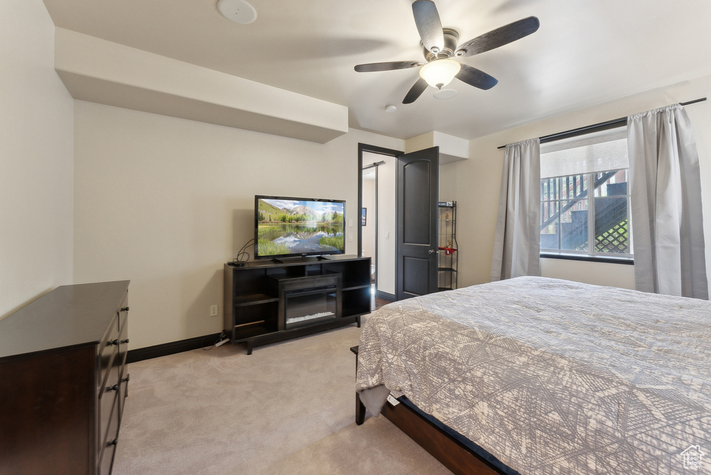Bedroom featuring light colored carpet, baseboards, and a ceiling fan