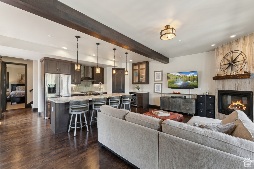 Living area with beam ceiling, recessed lighting, dark wood-style flooring, a large fireplace, and baseboards