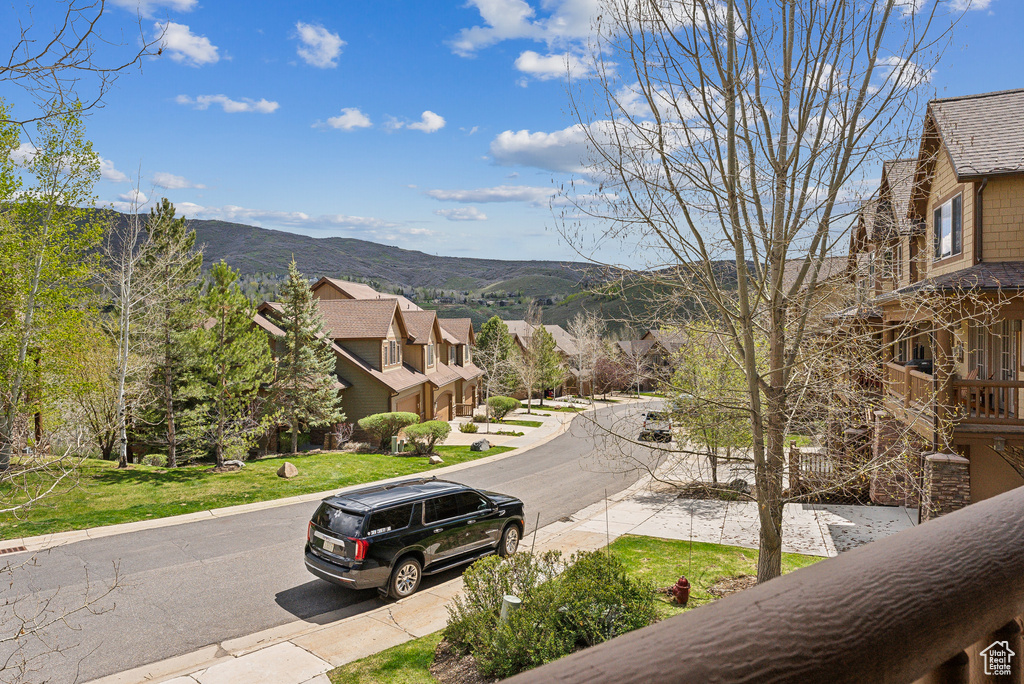 View of asphalt road with a mountain view, curbs, and a residential view