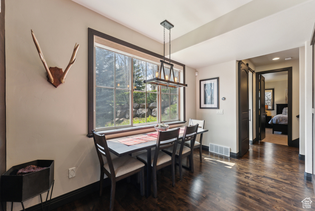 Dining area featuring dark wood-style floors, a barn door, and baseboards