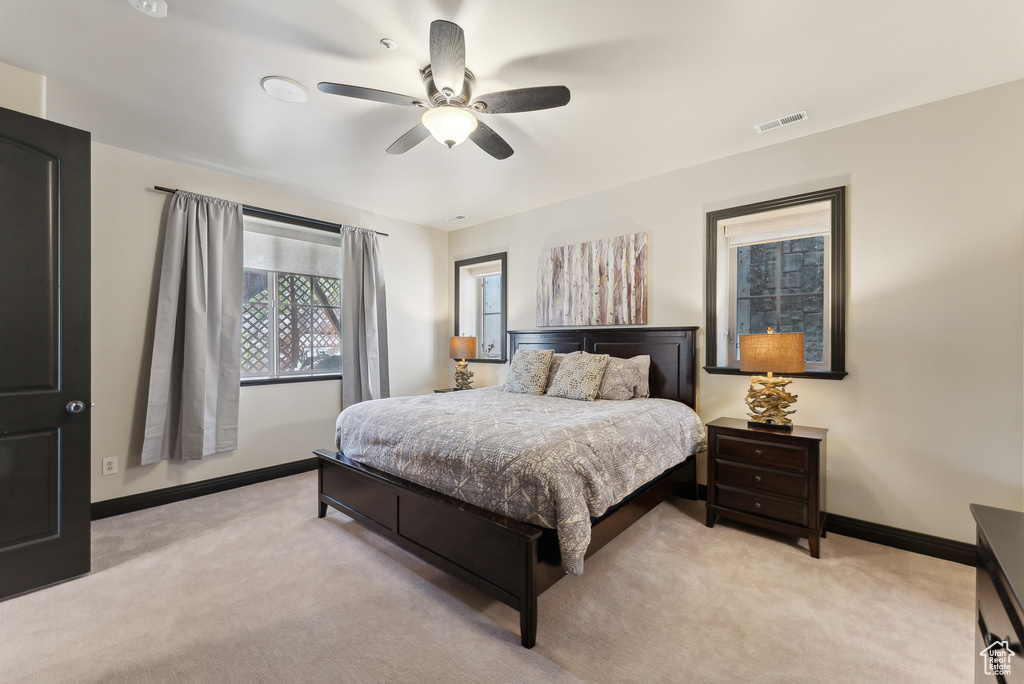 Bedroom featuring light colored carpet, baseboards, and ceiling fan