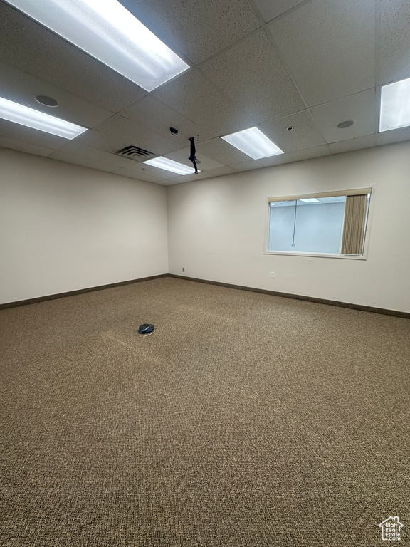 Carpeted spare room with baseboards and a drop ceiling