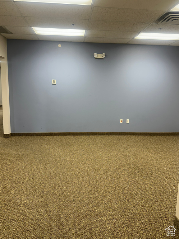 Carpeted empty room with a drop ceiling and baseboards