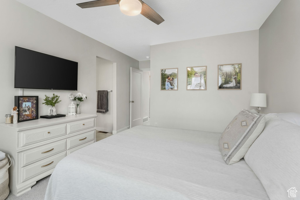 Bedroom featuring light carpet, a ceiling fan, and baseboards
