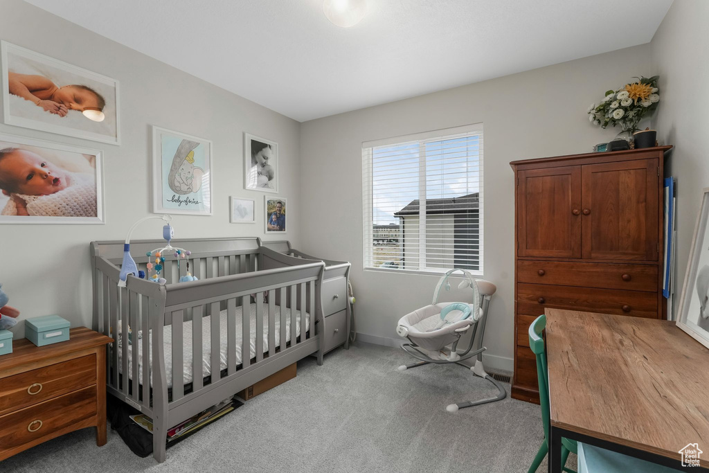 Carpeted bedroom featuring baseboards and a nursery area