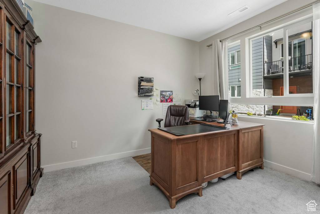 Home office with baseboards and light colored carpet