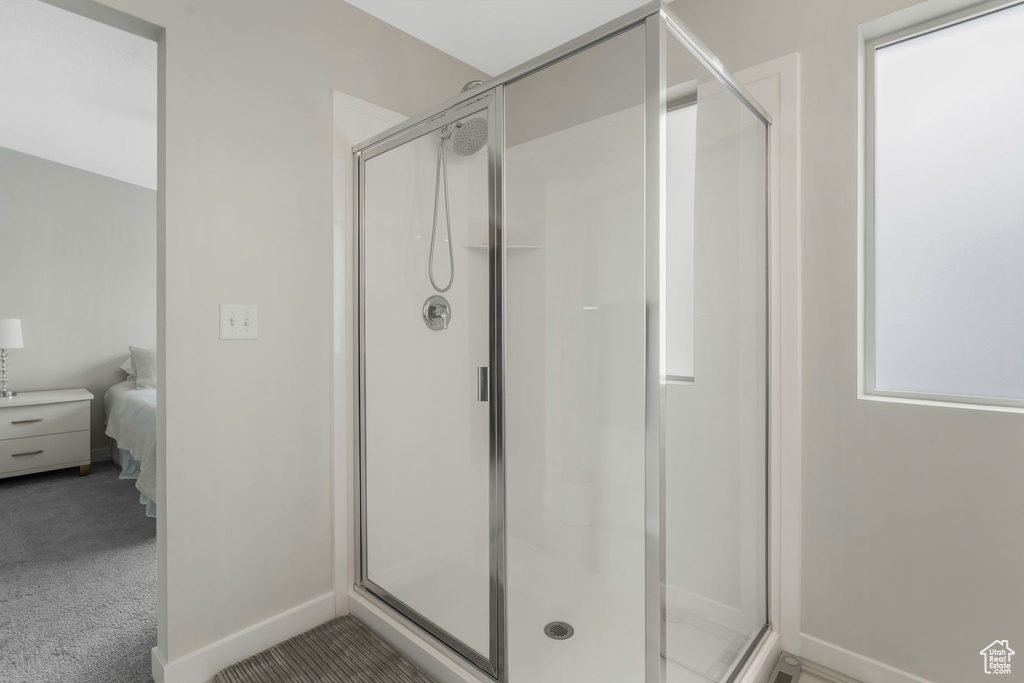 Ensuite bathroom featuring a shower stall and baseboards