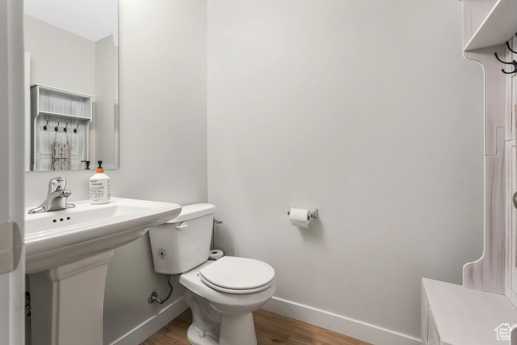 Bathroom with baseboards, wood finished floors, and toilet