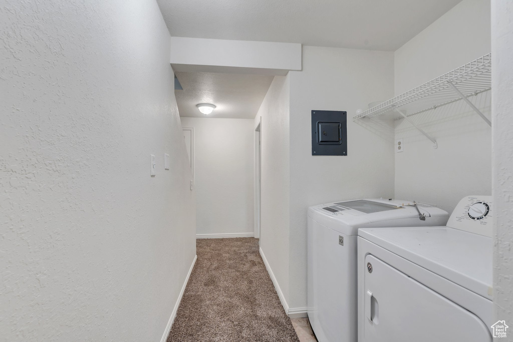 Laundry room with electric panel, light carpet, washer and dryer, and baseboards