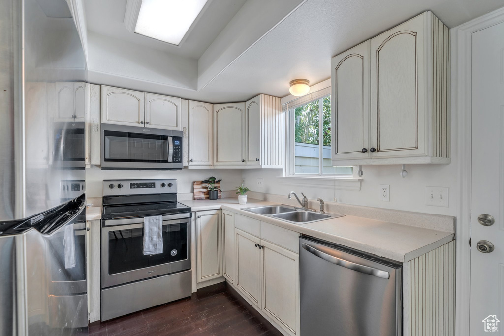 Kitchen featuring stainless steel appliances, a sink, light countertops, and dark wood-style flooring