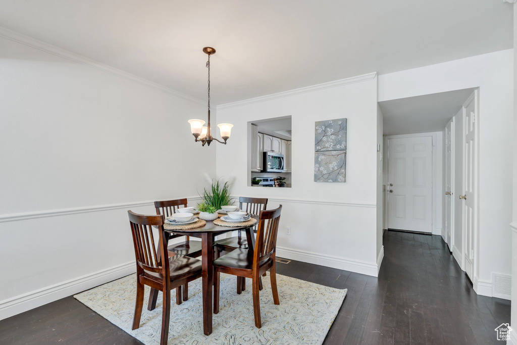 Dining room featuring hardwood / wood-style floors, crown molding, a chandelier, and baseboards