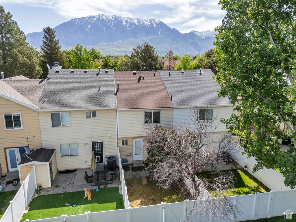 Rear view of house featuring a patio, a mountain view, roof with shingles, cooling unit, and a chimney