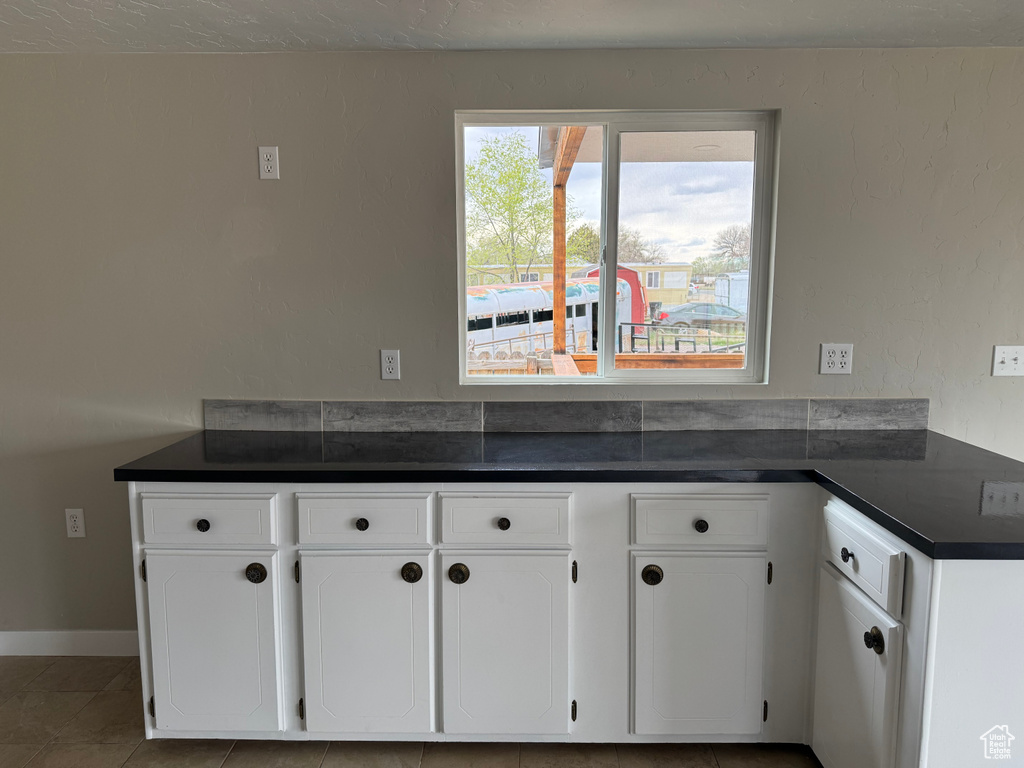 Kitchen featuring dark countertops, white cabinets, and tile patterned flooring