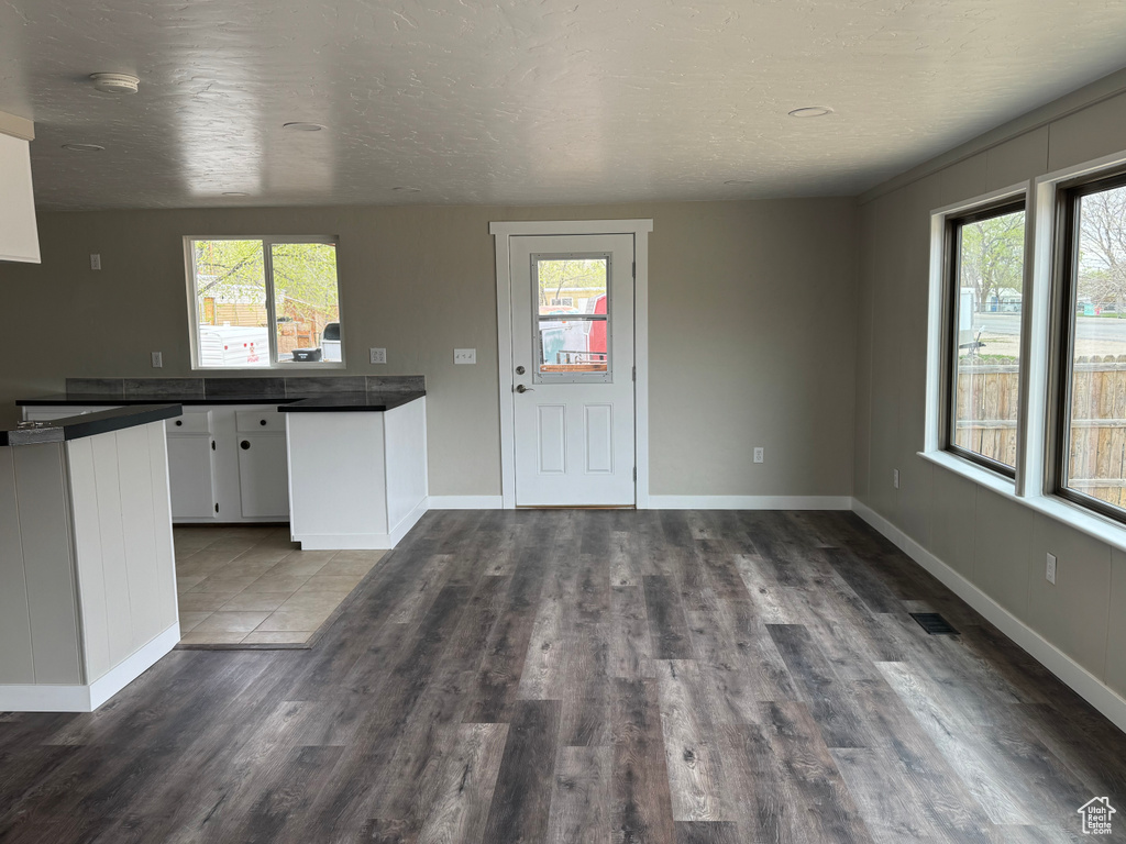 Kitchen with visible vents, dark wood-style floors, white cabinets, baseboards, and dark countertops