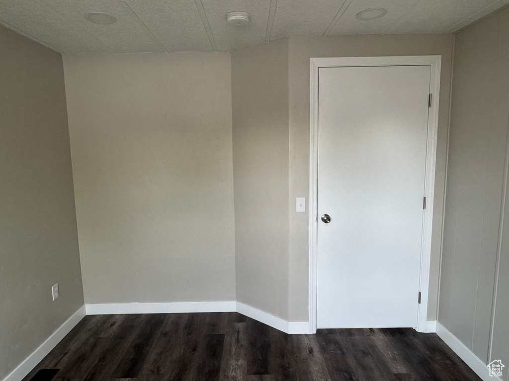Empty room with baseboards and dark wood-style floors