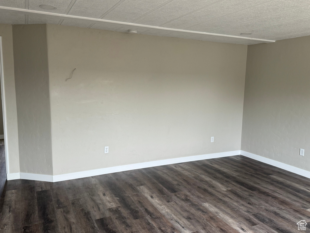 Empty room with baseboards and dark wood-style floors