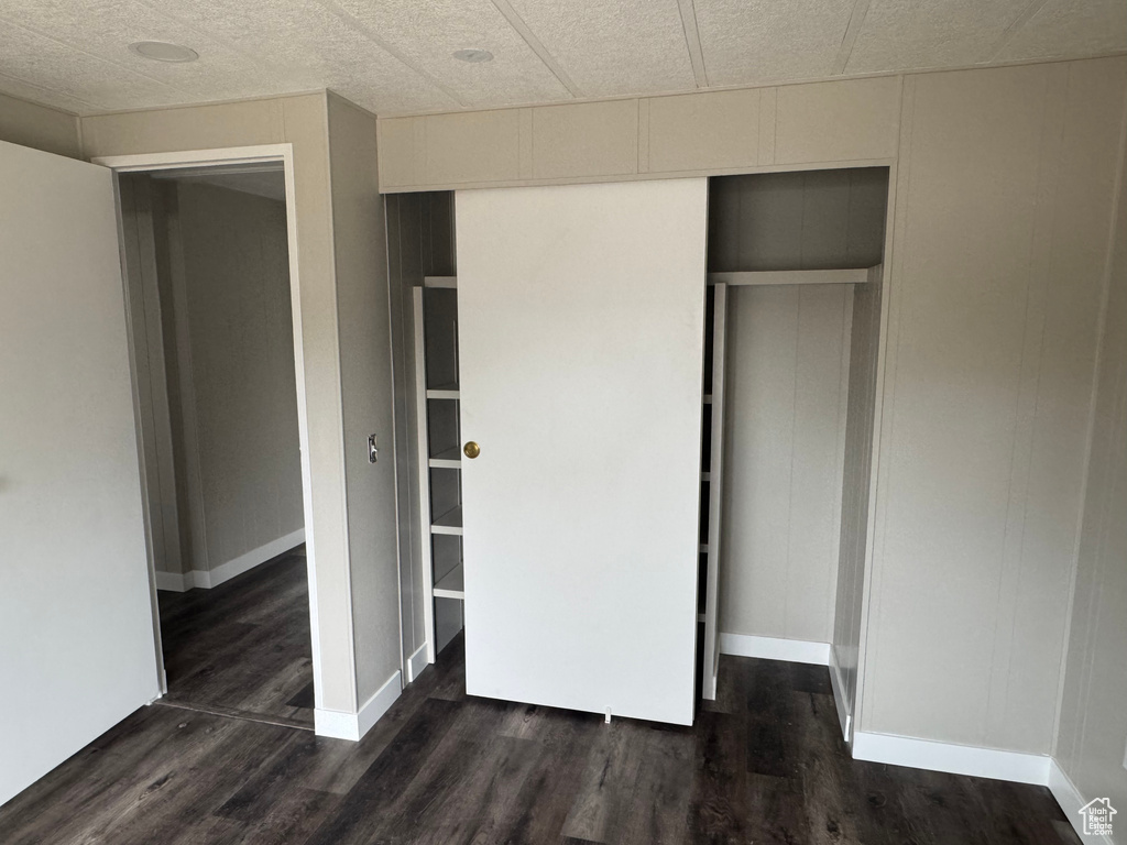 Unfurnished bedroom with baseboards, a closet, and dark wood-type flooring