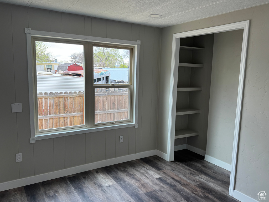 Interior space with a textured ceiling, dark wood-style flooring, and baseboards