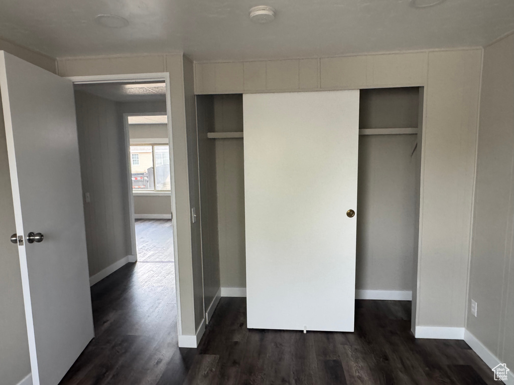 Unfurnished bedroom featuring baseboards, dark wood-style flooring, and a closet