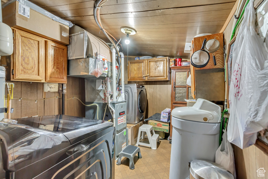 Basement featuring light floors, wooden ceiling, and washing machine and dryer