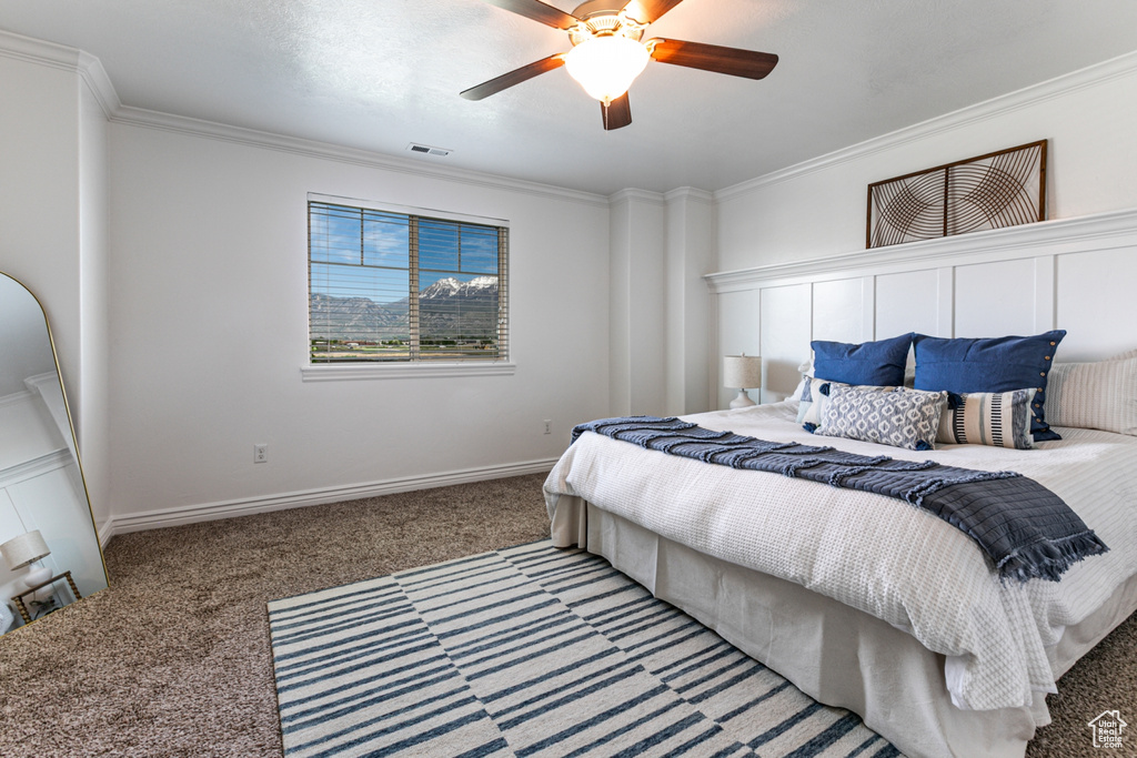 Carpeted bedroom featuring crown molding, a ceiling fan, and baseboards