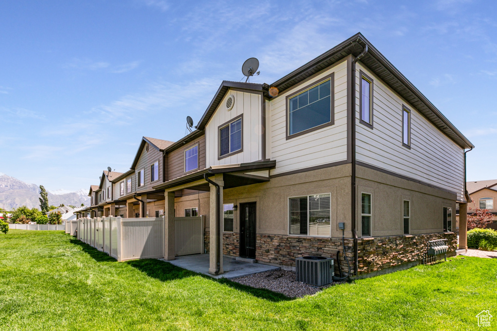 Rear view of property featuring stone siding, a mountain view, central AC, a patio area, and stucco siding