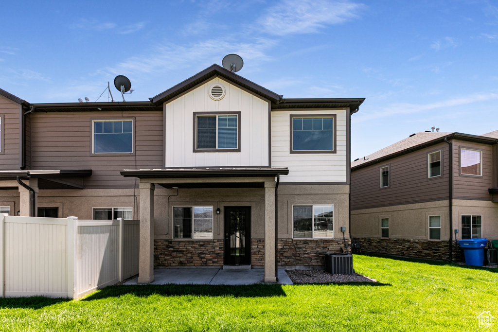 Back of property featuring a patio, stone siding, and board and batten siding