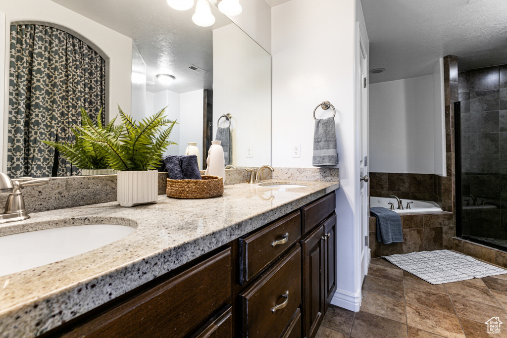 Full bathroom with double vanity, a bath, a shower stall, a textured ceiling, and tile patterned floors