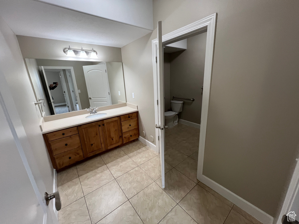 Bathroom featuring toilet, vanity, and tile patterned floors