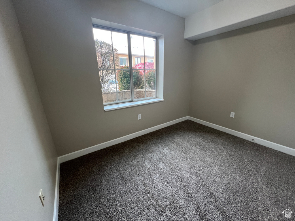 Carpeted spare room featuring baseboards