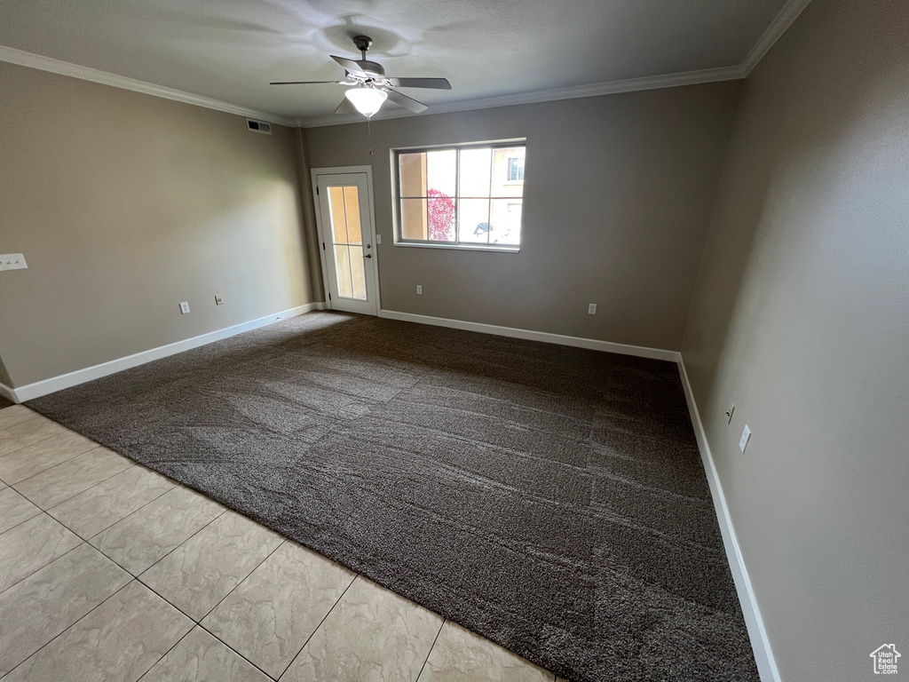 Carpeted empty room with ceiling fan, ornamental molding, and baseboards