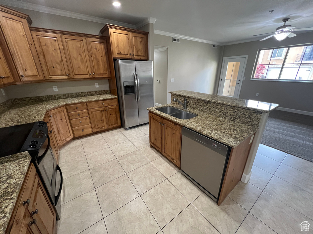 Kitchen with stainless steel appliances, a sink, brown cabinetry, a ceiling fan, and light tile patterned flooring