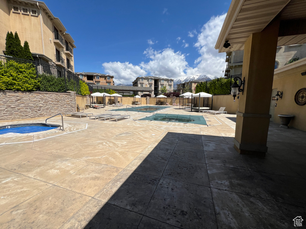 Community pool featuring a hot tub, a patio, a residential view, and fence