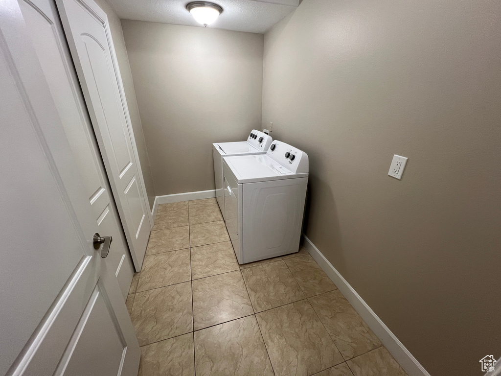Laundry room featuring washer and clothes dryer, baseboards, and light tile patterned floors