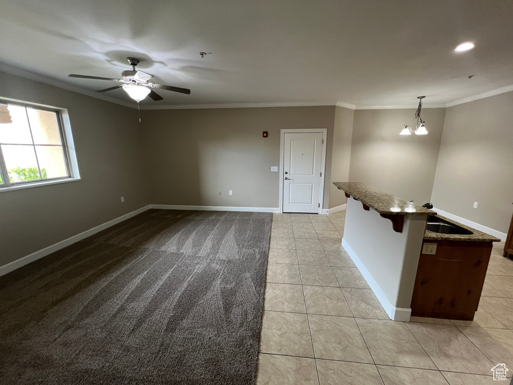 Unfurnished room featuring crown molding, a ceiling fan, light tile patterned floors, and baseboards