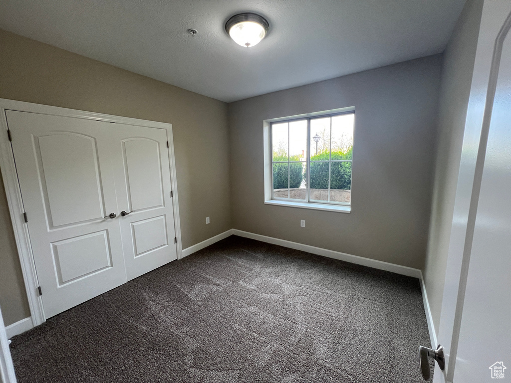 Unfurnished bedroom featuring dark colored carpet and baseboards