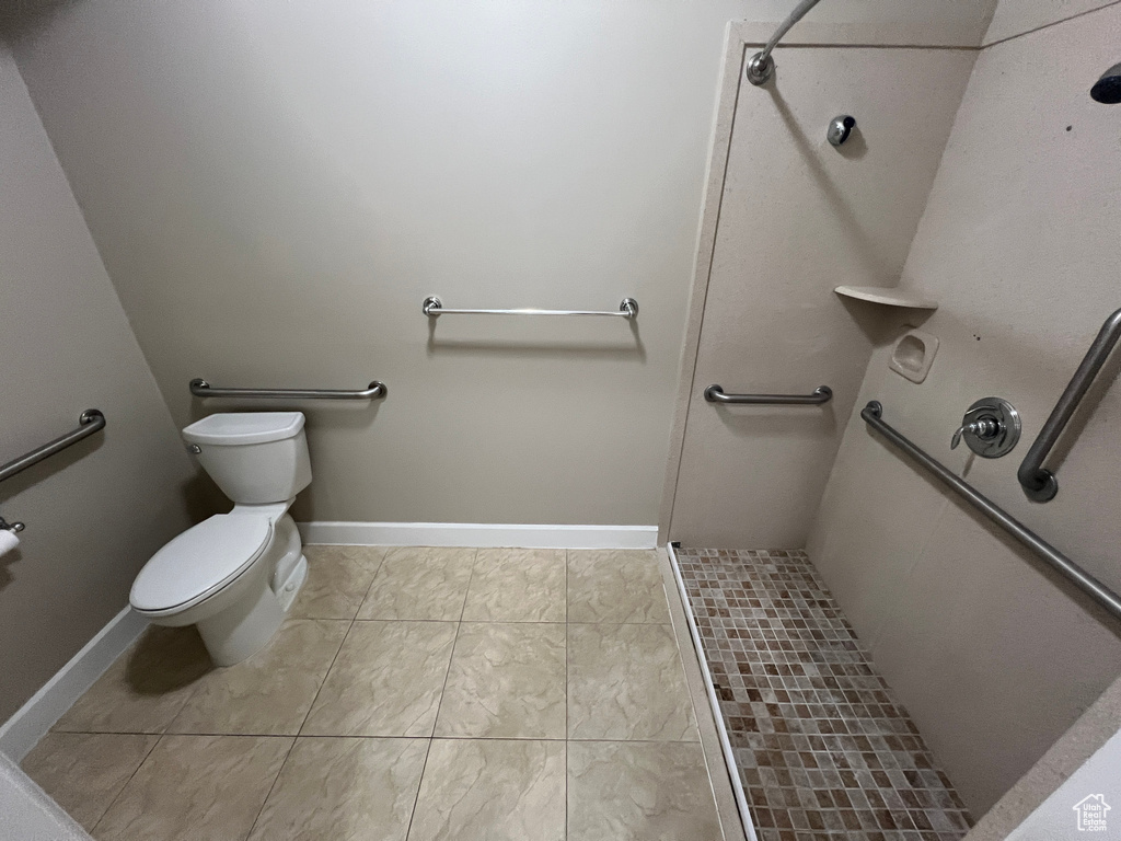 Full bathroom with a shower stall, toilet, and tile patterned floors