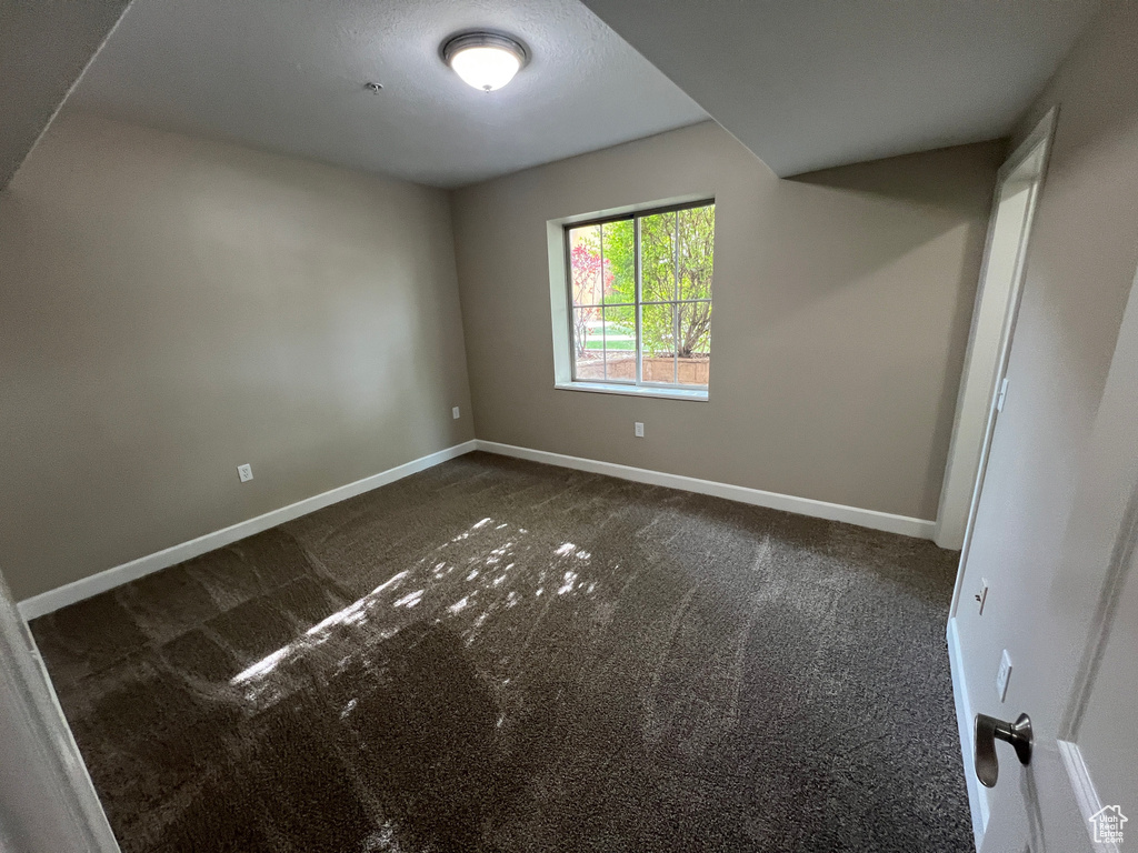 Empty room featuring dark colored carpet and baseboards