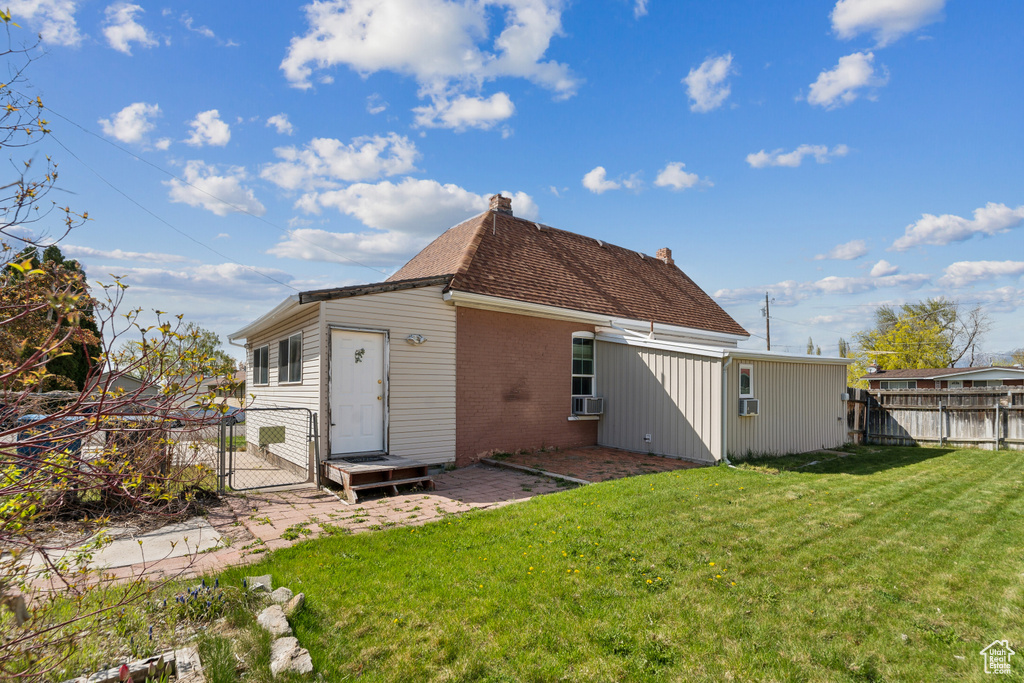 Rear view of house with brick siding, a gate, a chimney, and a patio