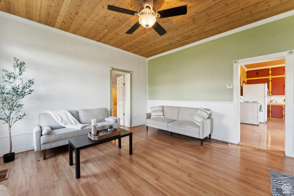 Living room with ornamental molding, a ceiling fan, wood finished floors, a wainscoted wall, and wooden ceiling