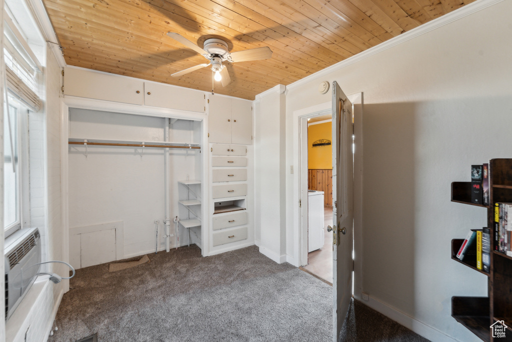 Unfurnished bedroom featuring wooden ceiling, carpet, washer / dryer, a closet, and an AC wall unit