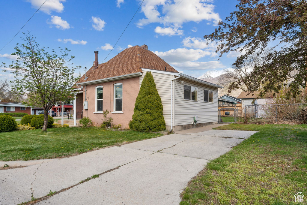 View of side of home with a chimney, brick siding, and concrete driveway