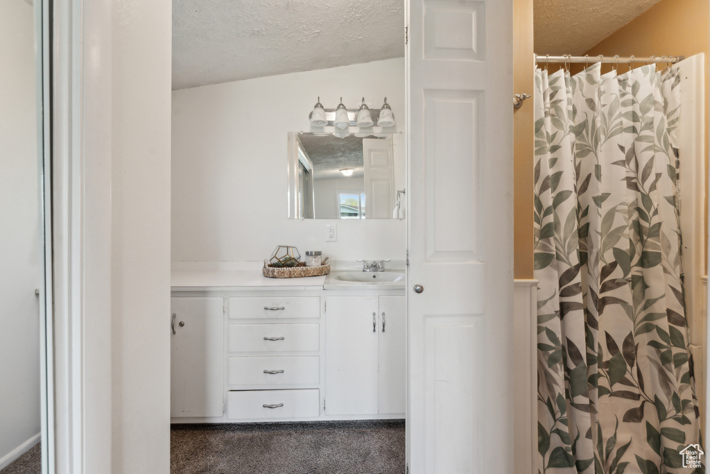 Full bathroom featuring a textured ceiling, vanity, and curtained shower